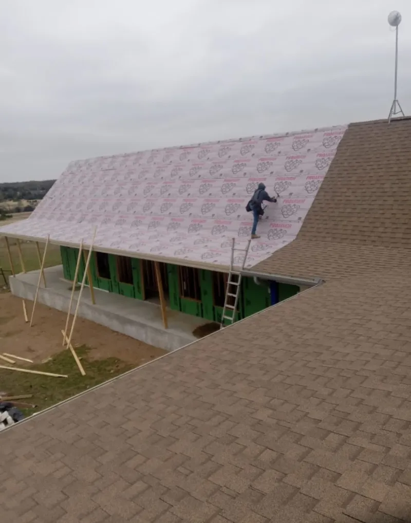 Worker preparing underlayment for a metal roof installation in Apple Valley